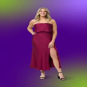 Kerry Cashman wearing a burgundy dress and posing against a purple and green studio background